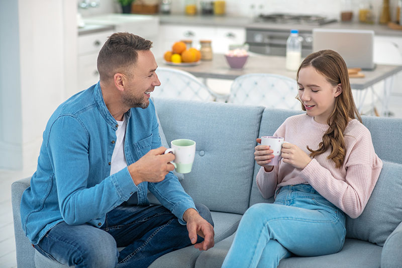 Dad And Daughter Are Cute Talking Sitting On The Couch.